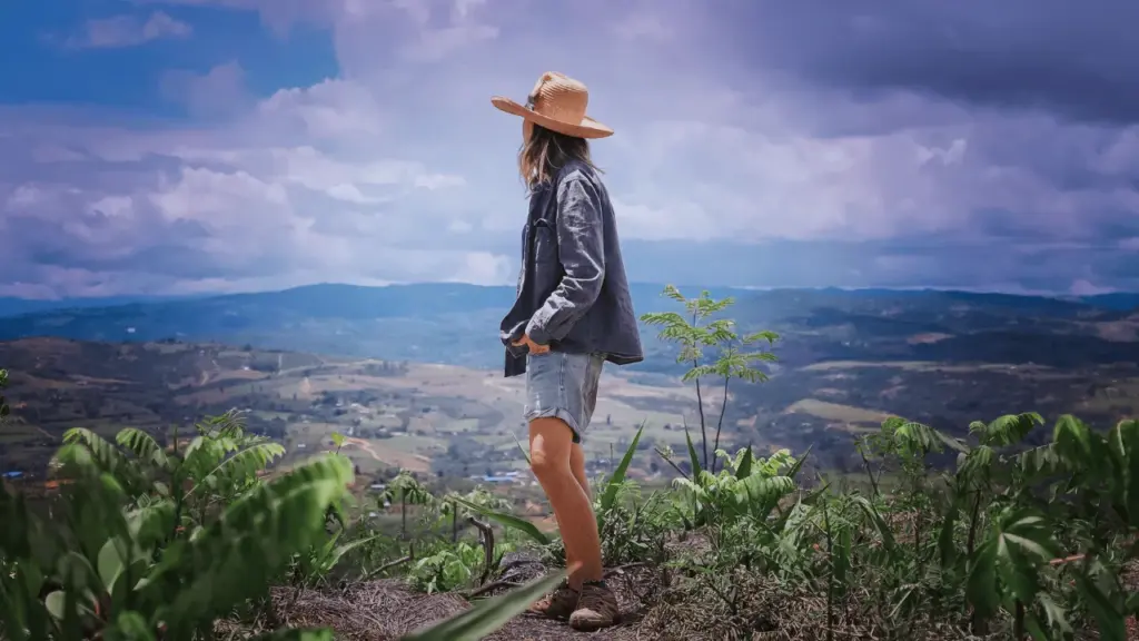 Cuidado del medio ambiente en zonas rurales, mujer en un campo de plantas verdes, protección de la biodiversidad y sostenibilidad en comunidades agrícolas para historias regenerativas.